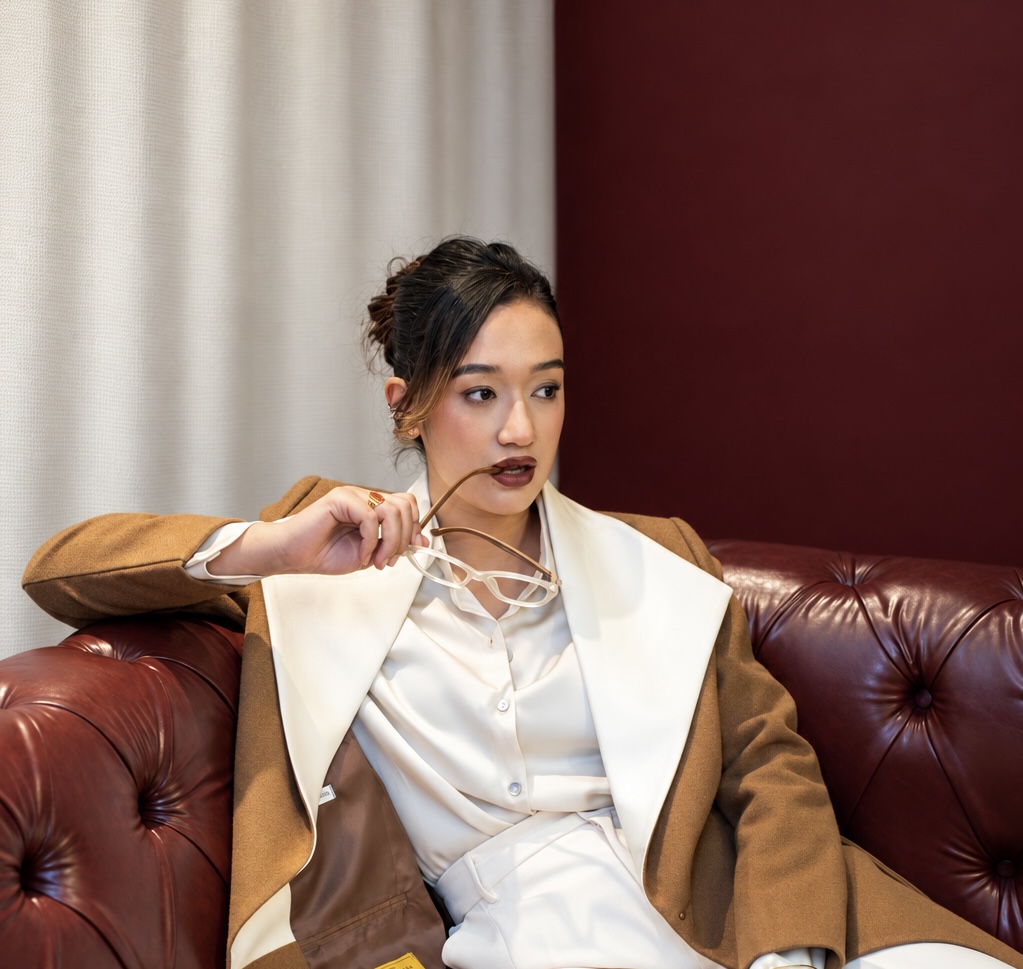 Shrija Shrestha on a leather sofa, holding her glasses